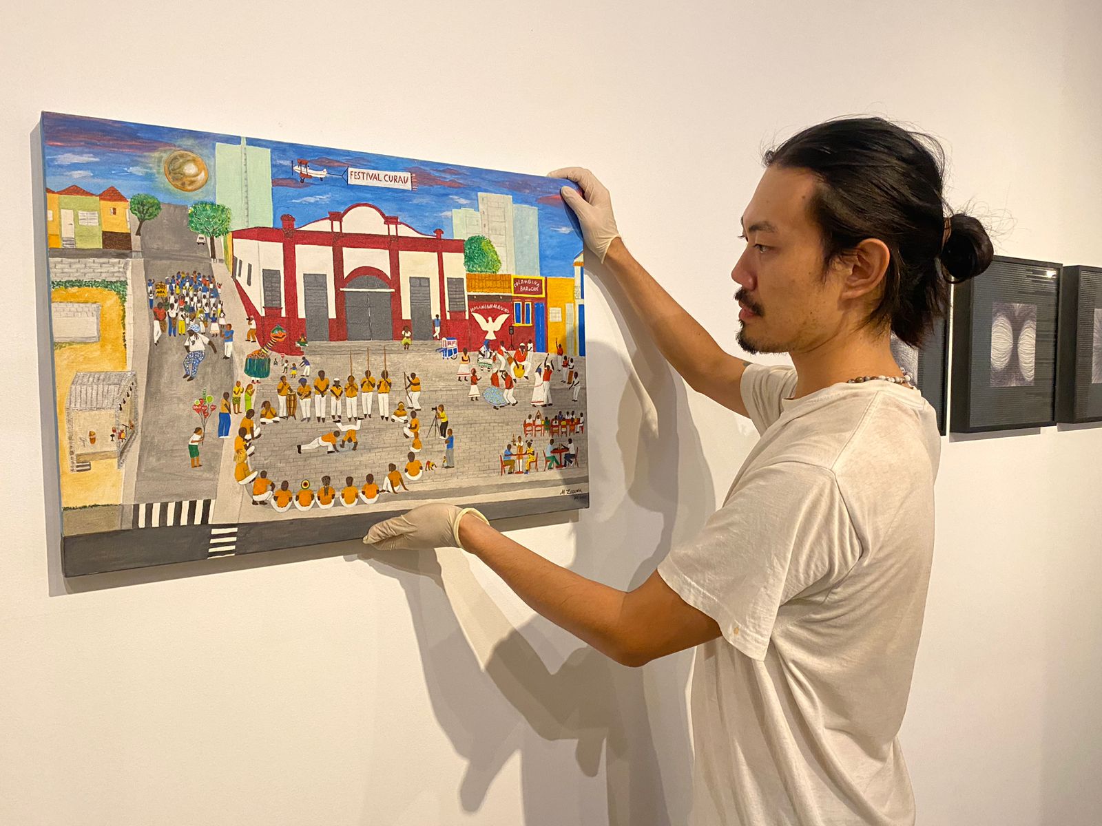 Homem, de descendência oriental, segura quadro em uma parede branca