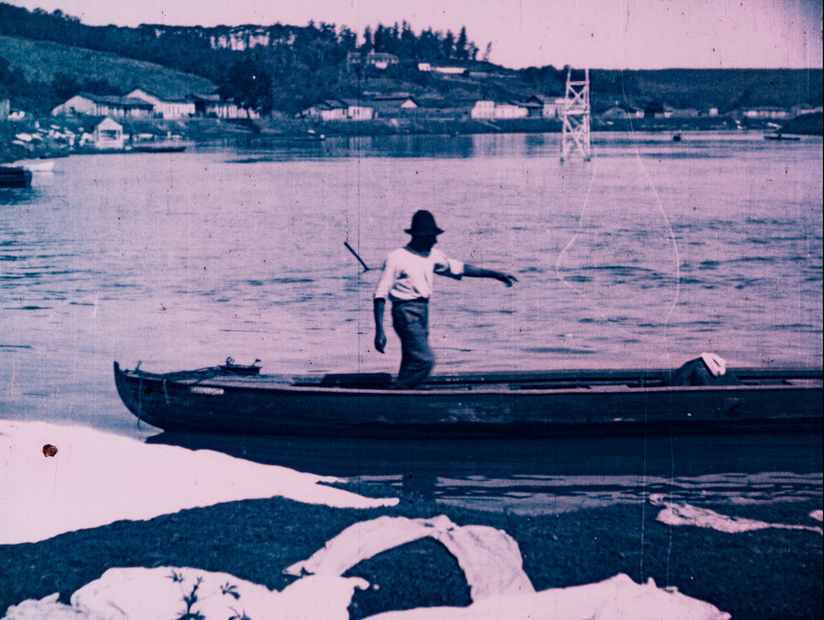 Homem em um barco em uma imagem cor sépia, no meio de um rio