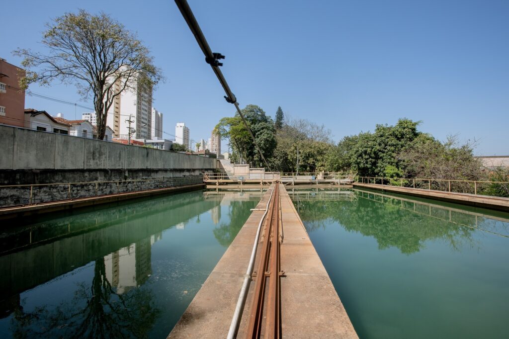 Estação de tratamento de tratamento tendo ao lado um muro e diversas árvores.