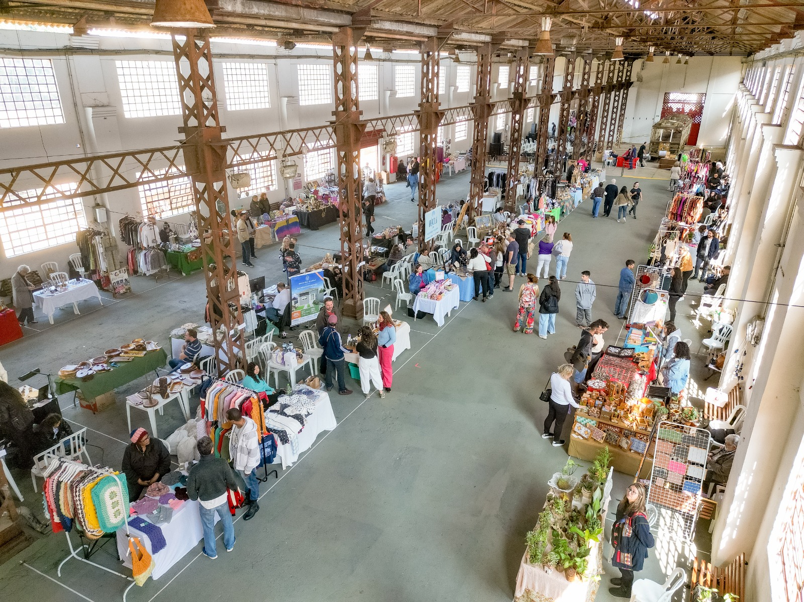 Foto de cima do Armazém 9, do Engenho Central; no solo estão barracas de feira de empreendimento com pessoas em volta