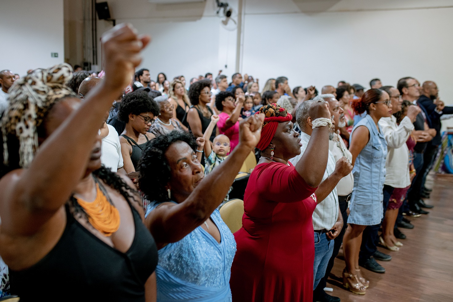 Mulheres e homens levantam o punho em alusão ao Hino da Negritude