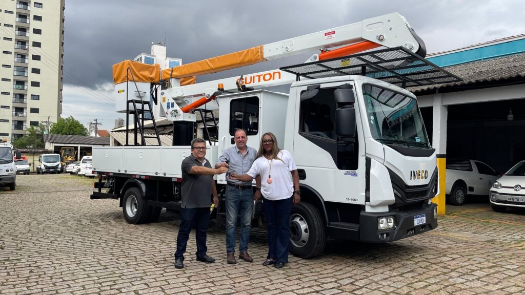 Tendo um caminhão branco ao fundo, o secretário da Semozel ao centro, recebe as chaves do veículo.