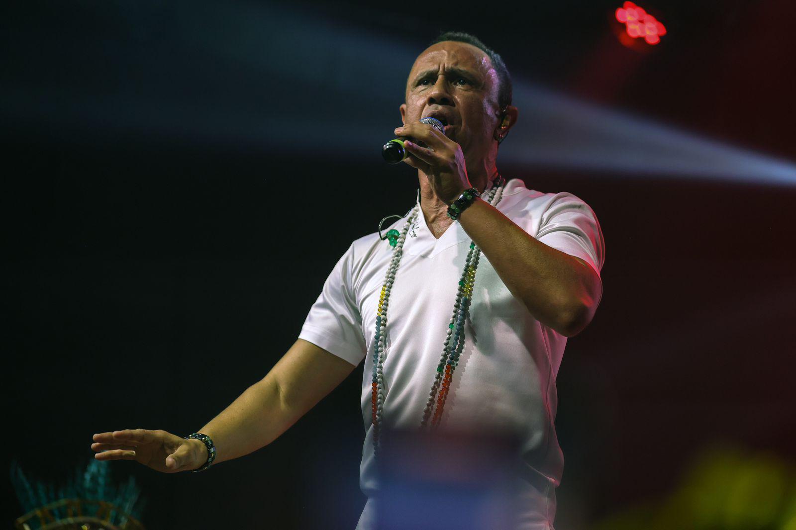 Homem de camiseta branca com microfone em uma mão