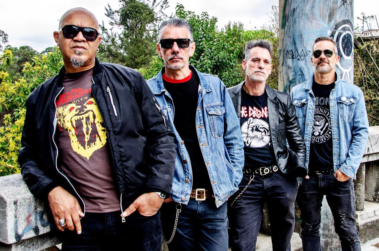 Quatro homens perfilados com jaquetas, que formam uma banda