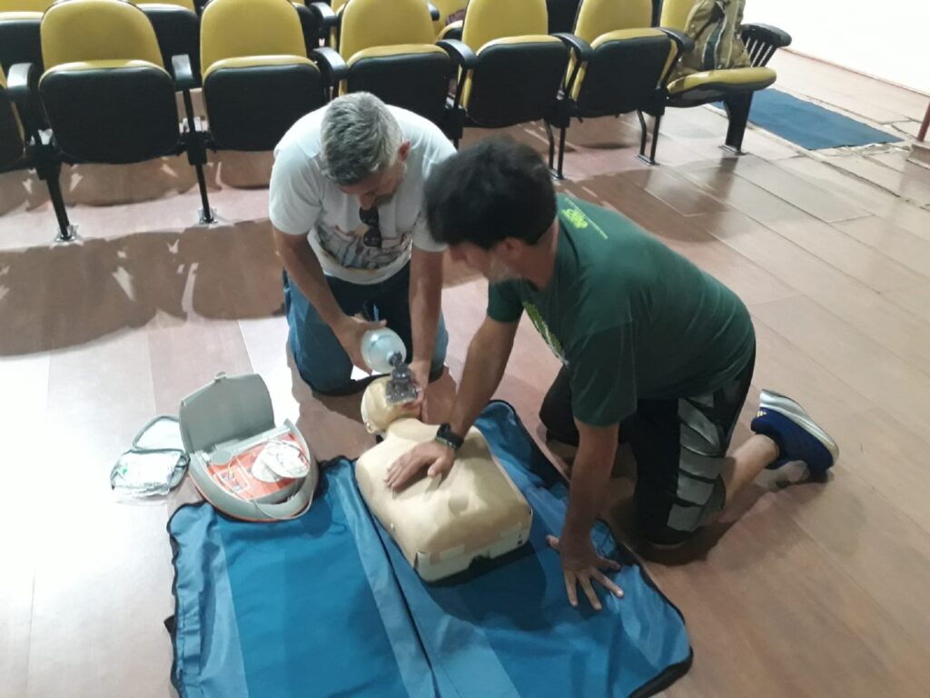 Servidores brigadistas durante o curso, realizando realizam em boneco de plástico, medida de primeiros socorros, com uma máscara de silicone tampando a boca er o nariz.