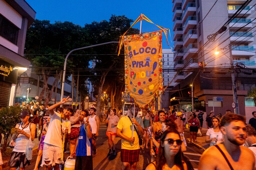 diversas pessoas em uma rua, no período notuno, celebrando o Carnaval