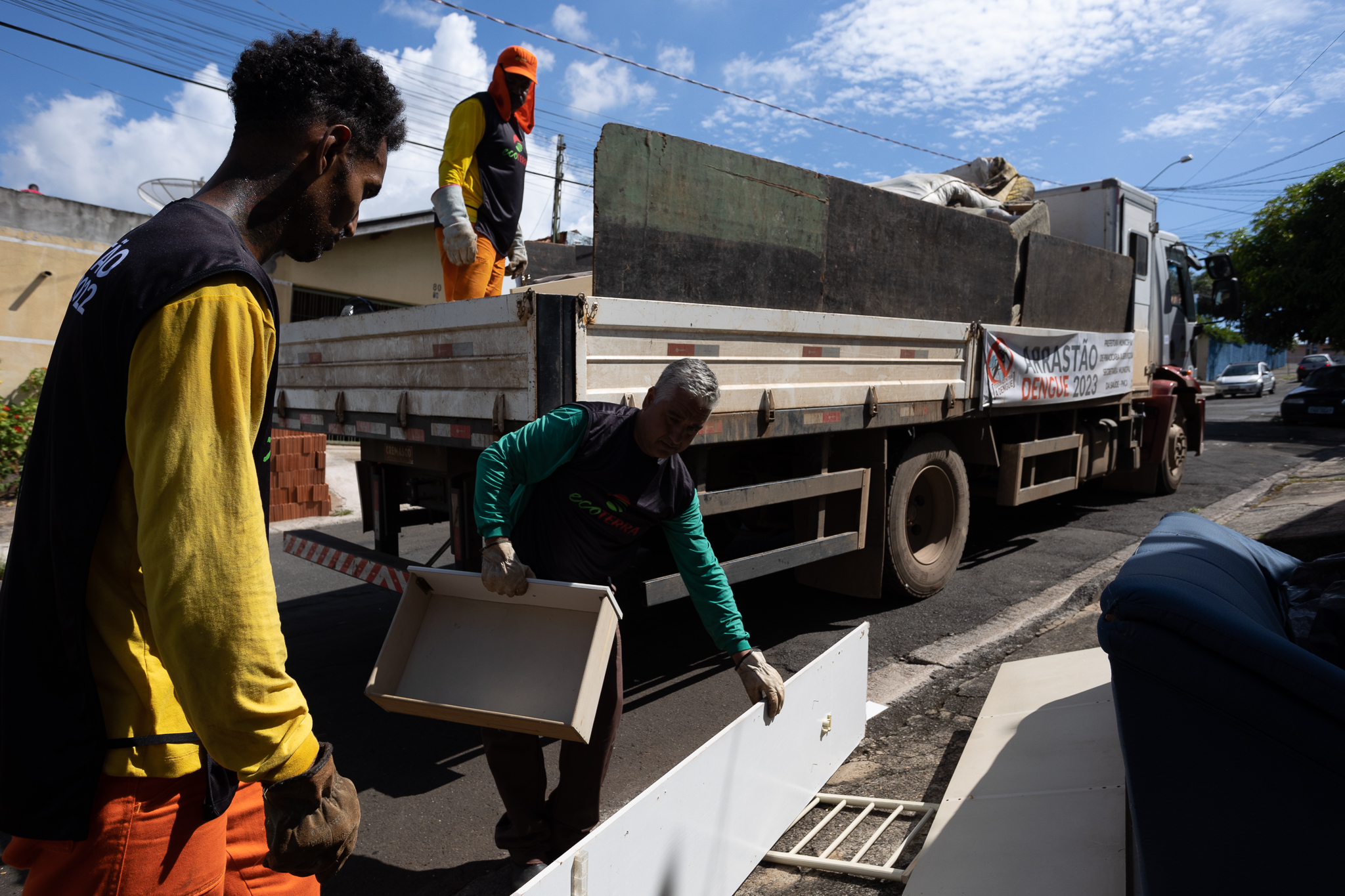 Homens da prefeitura coletam materiais das ruas e colocam no caminhão para evitar criadouros da dengue