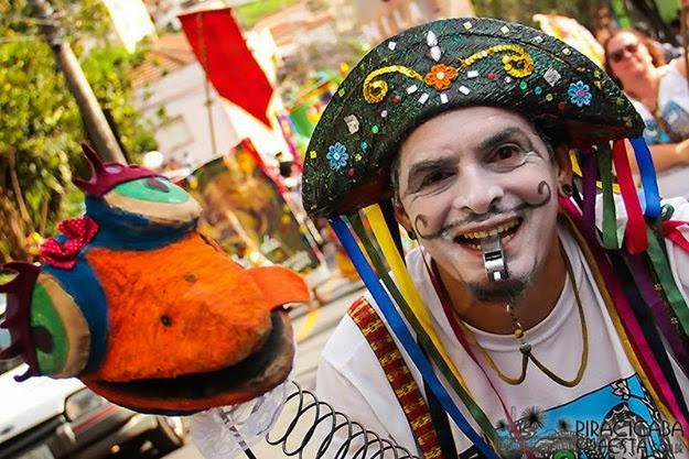 Tony Azevedo, artista e criador do Bloco da Ema, aparece sorridente com figurino colorido de cultura popular. Ele é responsável pela criação da XiloFeira e coordena a programação cultural.