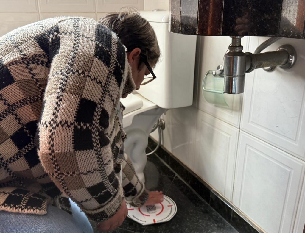 Uma mulher de blusa xadrez cobra um ralo com adesivo