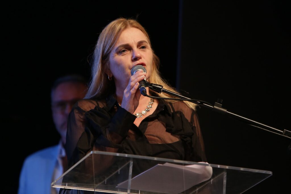 Primeira-dama Valkíria Callovi fala ao microfone em púlpito durante solenidade do Salão.