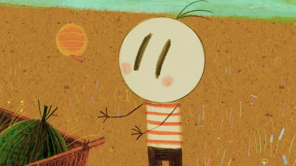 A imagem exibe um estilo de arte infantil, com um traço simples e cores vibrantes. O cenário parece ser um campo, com um horizonte de cor verde-água no topo e um tom de ocre predominante no restante da imagem, que simula a terra. Pequenas hastes de grama e flores em tons pastéis, como rosa, azul e amarelo, pontilham o campo, dando um toque delicado. No centro da imagem, um personagem principal se destaca. Ele tem uma cabeça redonda e branca, com dois traços verticais escuros para os olhos e duas manchas rosadas nas bochechas. Seu corpo é um tronco listrado em vermelho e branco, e ele veste uma calça marrom. Seus braços são finos e escuros, com mãos pequenas e de três dedos, uma delas estendida em um gesto de saudação ou movimento. À esquerda do personagem, parcialmente visível, há uma cesta de vime com um objeto verde e pontiagudo dentro, que lembra um vegetal ou uma planta estilizada. Ao fundo, um pouco acima e à esquerda do personagem, flutua um objeto esférico de cor laranja, com linhas que indicam sua textura e duas pequenas tiras vermelhas penduradas, lembrando um balão ou uma lanterna. O estilo geral da imagem é lúdico e alegre, com uma textura que sugere papel ou tela pintada.