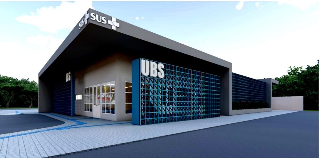 A imagem mostra uma renderização arquitetônica moderna de uma unidade básica de saúde (UBS). O edifício tem um design contemporâneo e minimalista, com linhas retas e cores neutras predominantes, como cinza claro e branco. A fachada principal possui grandes portas e janelas de vidro com molduras brancas, proporcionando um ambiente claro e acolhedor. Um dos destaques visuais é uma parede lateral feita com blocos vazados azuis (cobogó), que também apresenta as letras grandes "UBS" em branco, tornando o local facilmente identificável. O telhado é plano e possui uma grande extensão na cor cinza escuro, criando uma espécie de beiral que protege a entrada. No topo do edifício, há um letreiro com a sigla "SUS" (Sistema Único de Saúde) acompanhada de um símbolo de cruz médica, reforçando a natureza do serviço público de saúde oferecido no local. O chão é pavimentado com blocos retangulares claros e há uma faixa azul que provavelmente indica acessibilidade. Ao fundo, é possível ver uma vegetação verde, que traz um aspecto natural e agradável ao entorno. O céu está claro, com poucas nuvens, sugerindo um dia ensolarado. A composição geral transmite uma sensação de modernidade, funcionalidade e acolhimento, características importantes para uma unidade de saúde pública.
