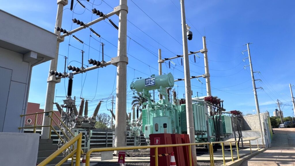 Na imagem aparece uma subestação elétrica com vários compartimentos. Na parte de cima aparece o céu azul.