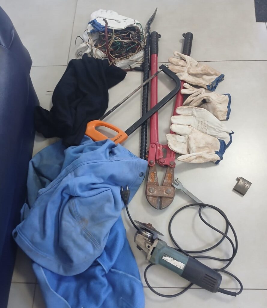 Na imagem aparecem diversos equipamentos como luvas, fios de cobre, um cortador e aparelho elétrico, colocados sobre uma mesa branca.