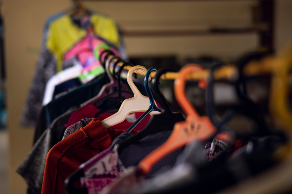 Na imagem aparecem diversas peças de roupas coloridas pendurada em cabides no varal