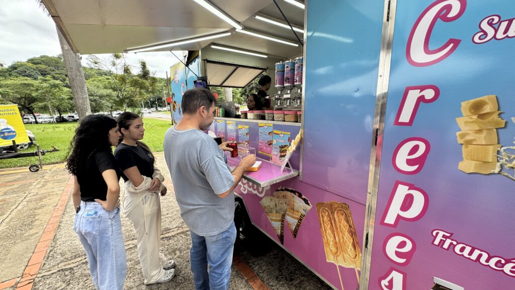 Clientes realizam pedidos em um trailer de crepes instalado em área pública, representando o segmento de alimentação participante do evento Sabores na Rua.