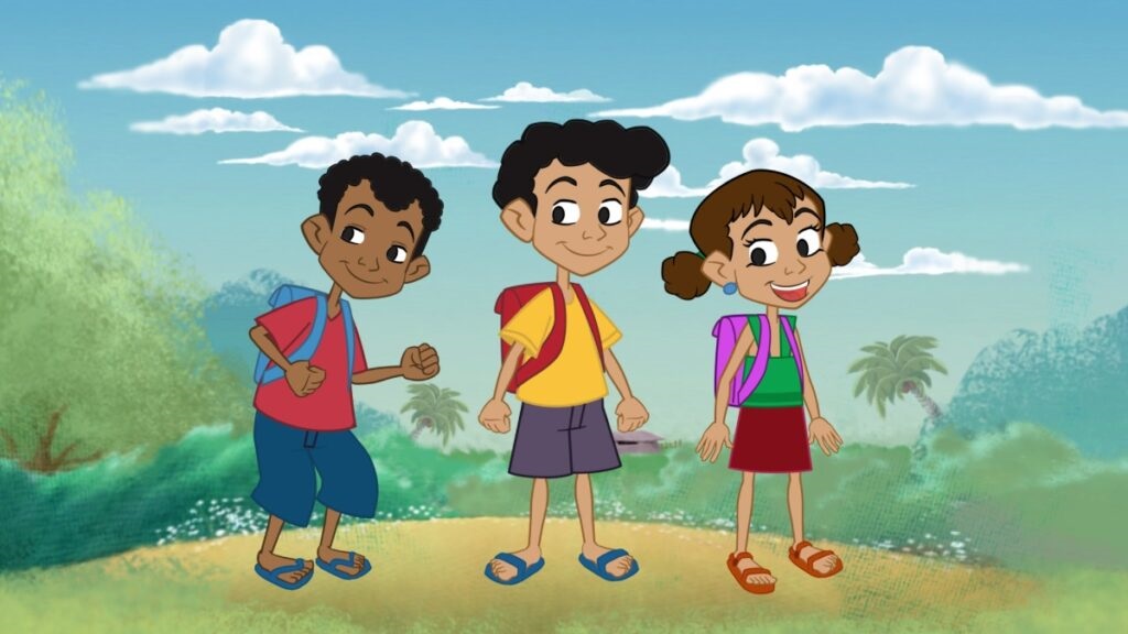 Três crianças em estilo cartoon em pé lado a lado num cenário ao ar livre, com ar alegre e descontraído. Criança à esquerda: menino de cabelos cacheados curtos, camiseta vermelha, bermuda azul-escura, chinelos azuis e mochila azul nas costas; postura levemente inclinada à frente, expressão sorridente. Criança ao centro: menino com cabelo preto e volumoso, camiseta amarela, bermuda cinza, chinelos azuis e mochila vermelha; olhar tranquilo e sorriso discreto. Criança à direita: menina com cabelos castanhos presos em dois coques laterais, brincos azuis, regata verde, saia vermelha, sandálias laranja e mochila roxa; sorri abertamente. Cenário: terreno claro com vegetação baixa ao fundo, arbustos e palmeiras, céu azul com nuvens brancas esparsas — atmosfera ensolarada e tropical.