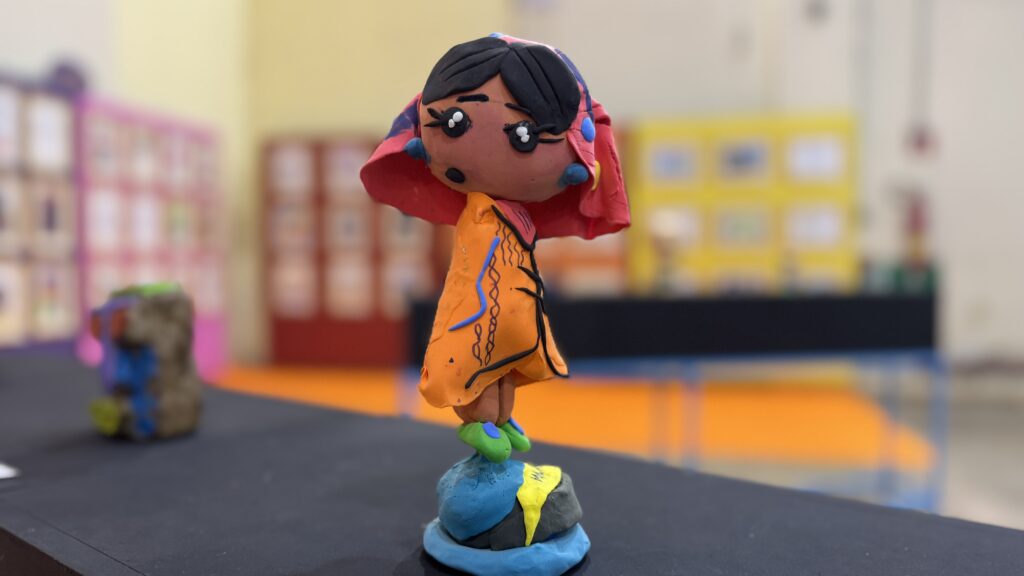 A imagem mostra uma pequena escultura artesanal feita de massa de modelar.