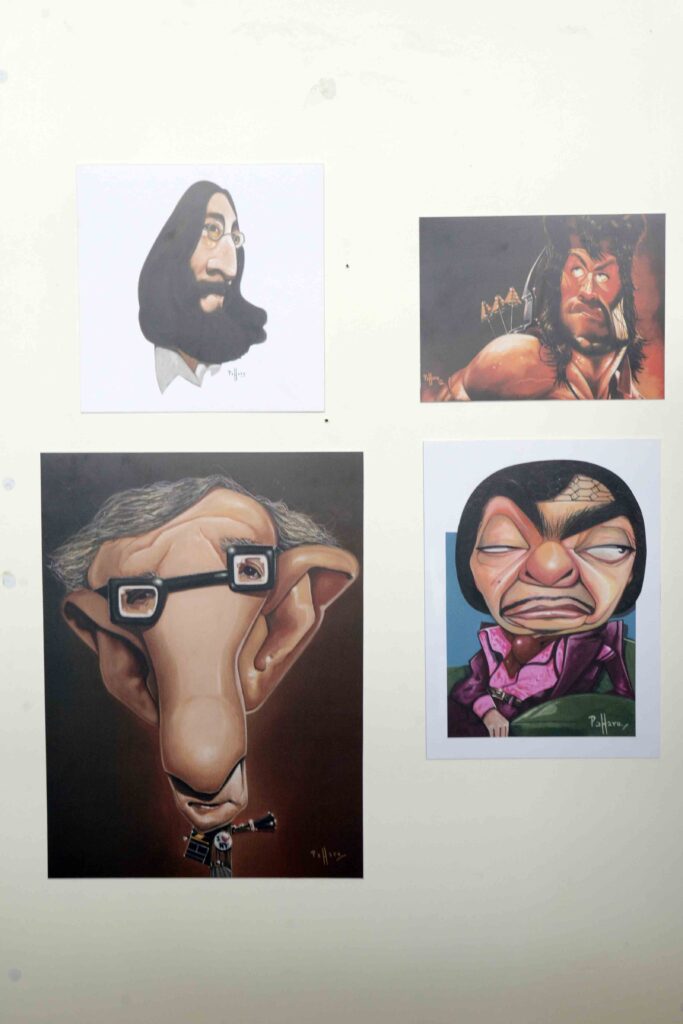 Parede expositiva com caricaturas coloridas de diferentes personagens, destacando traços faciais exagerados típicos do humor gráfico.