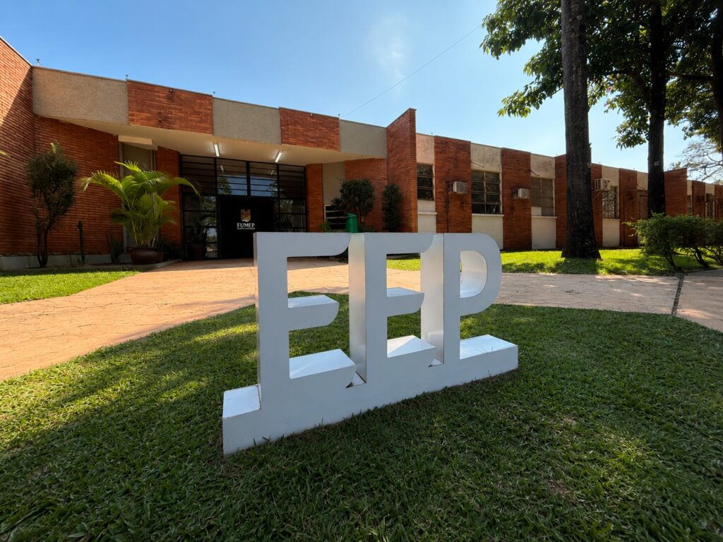 A fachada de tijolo à vista do edifício da EEP (Escola de Engenharia de Piracicaba/FUMEP) num dia ensolarado, com destaque para a sigla "EEP" em grandes letras tridimensionais brancas posicionadas no relvado em primeiro plano