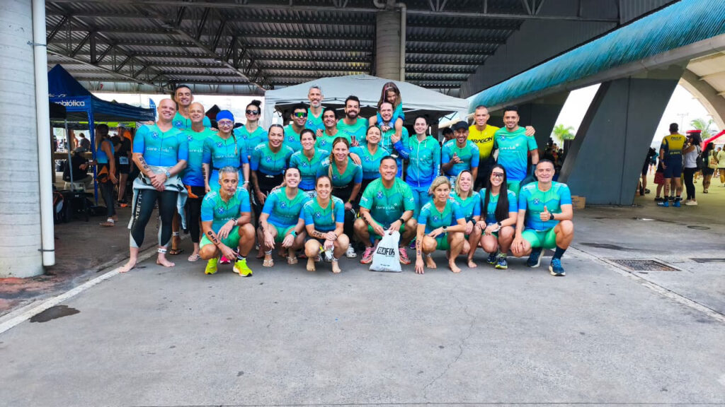 A imagem mostra um grande grupo de atletas reunidos para uma foto em equipe durante um evento esportivo.