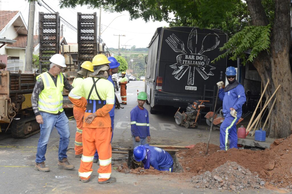 equipe técnica atua em uma escavação na rua, utilizando equipamentos de segurança durante a substituição ou ampliação da rede de água.