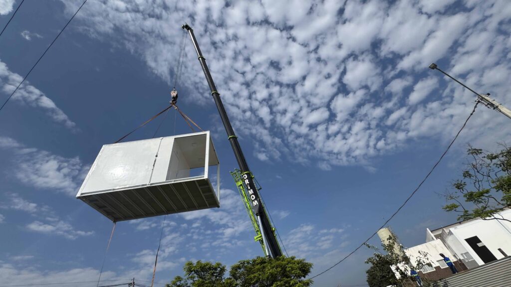 Guindaste ergue módulo pré-fabricado para posicionamento durante obra de expansão da unidade de saúde.