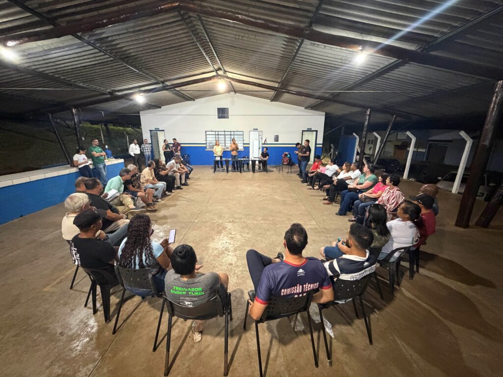 Vista ampla do encontro, mostrando moradores e representantes reunidos em círculo para discutir temas de interesse da comunidade em um ambiente aberto e iluminado.