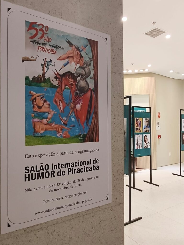 A imagem mostra um pôster do 53º Salão Internacional de Humor de Piracicaba, fixado em uma parede de uma galeria.