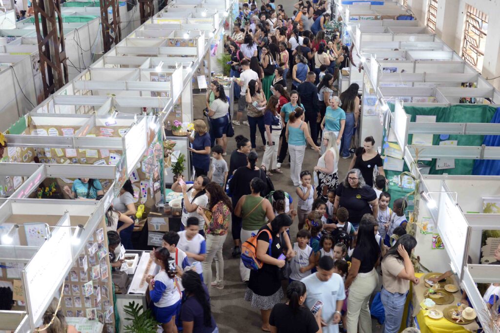 Perspetiva elevada dos corredores movimentados, evidenciando a grande presença de alunos, professores e famílias a visitar os projetos.