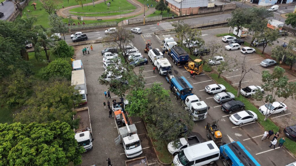 Vista aérea do parque de estacionamento que mostra a frota de camiões, tratores e veículos de apoio reunidos para a força-tarefa de zeladoria.