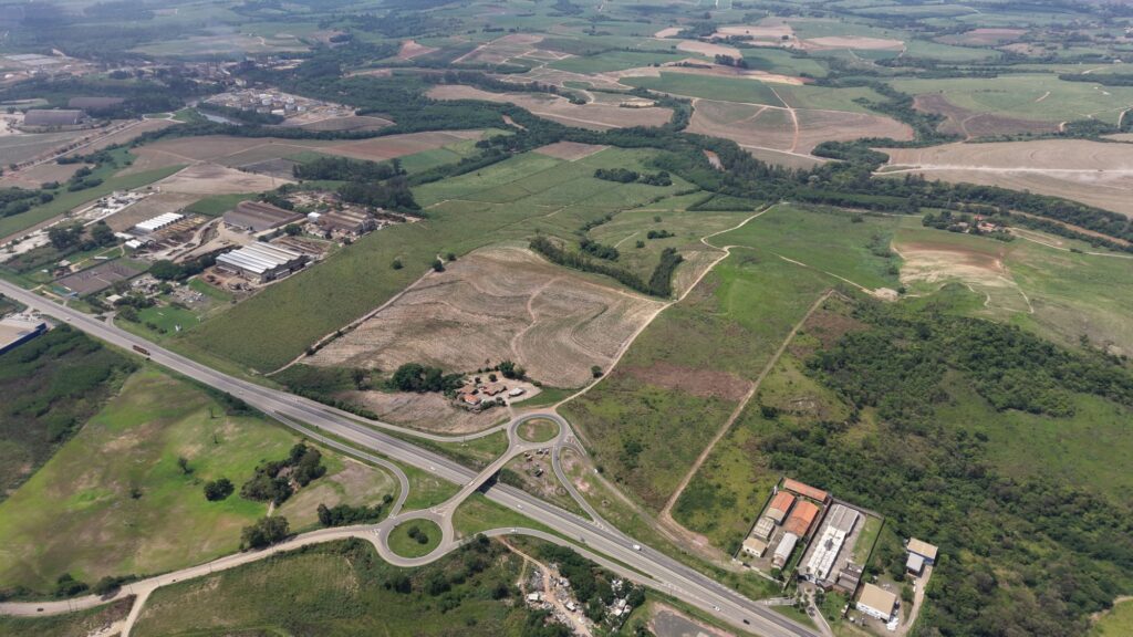 Vista aérea do dispositivo de acesso rodoviário com rotondas que interliga as rodovias municipais no bairro Santana, cercado por áreas agrícolas e instalações industriais.