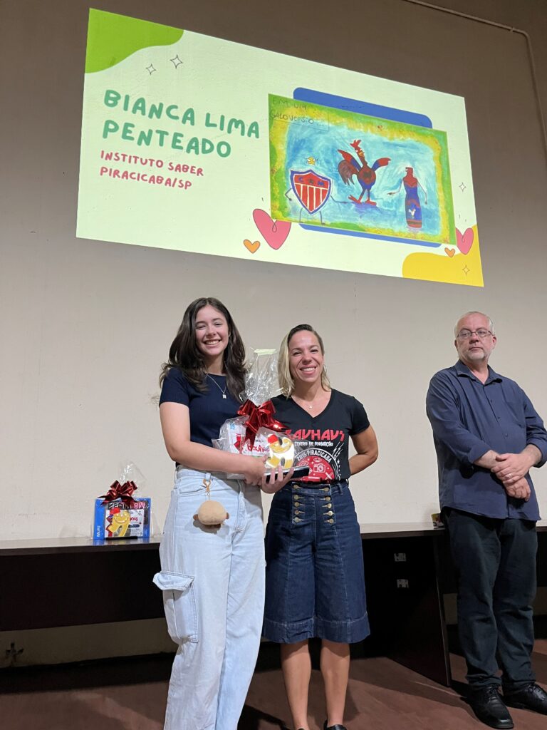 Bianca Lima Penteado recebe o prémio de 2.º lugar da categoria de 11 a 14 anos das mãos de Bruna Caritá.