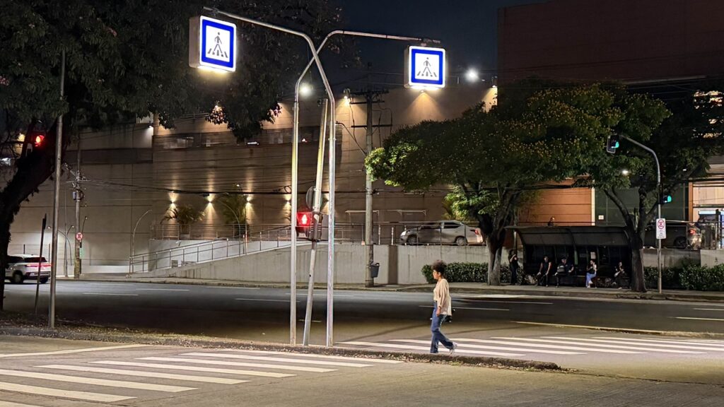 Uma pessoa atravessa a estrada na faixa sob a luz dos projetores.