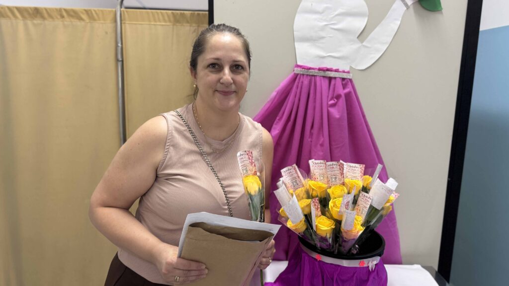 Graziele Patrezzi a segurar exames e uma flor amarela temática recebida na unidade de saúde.