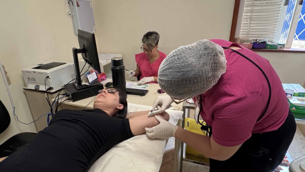 Uma profissional de saúde a realizar o procedimento de implantação do percutâneo contraceptivo Implanon no braço de uma paciente.