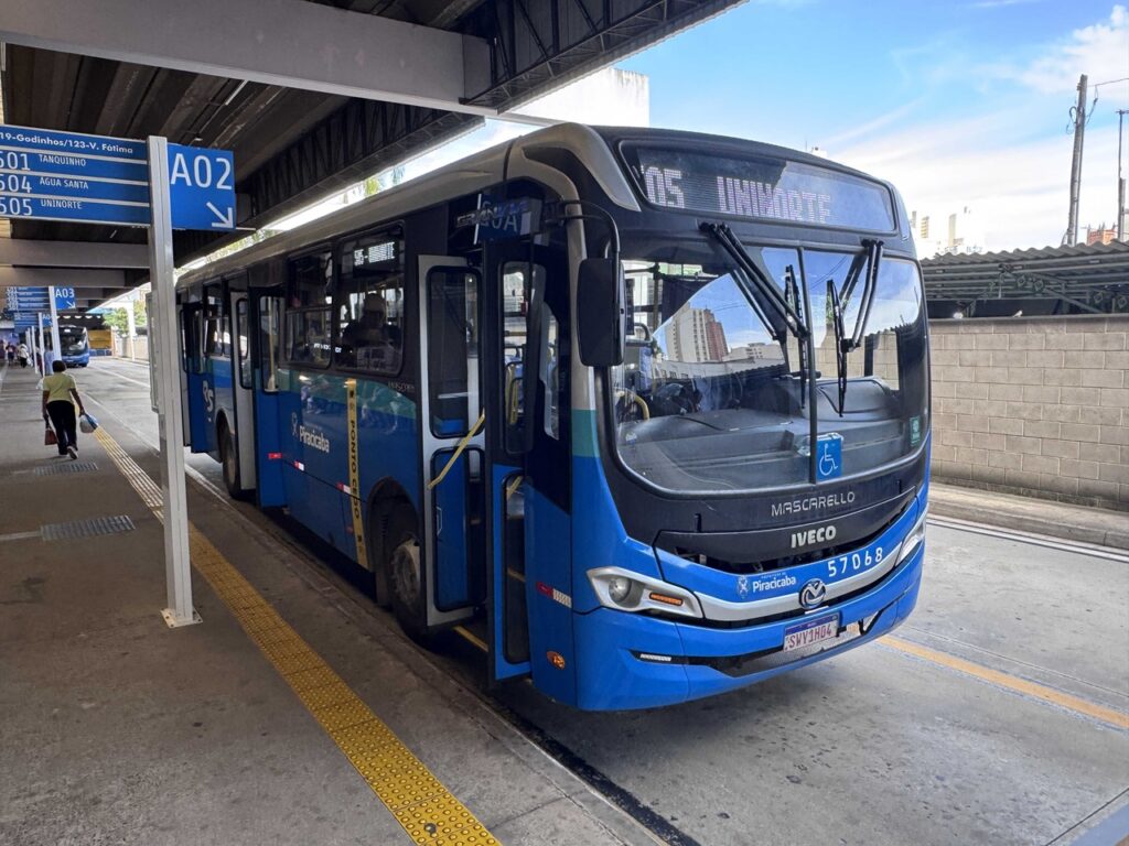 Um autocarro urbano azul e cinzento do transporte público de Piracicaba, indicando no letreiro a linha "05 UNINORTE", parado numa plataforma de embarque de um terminal.