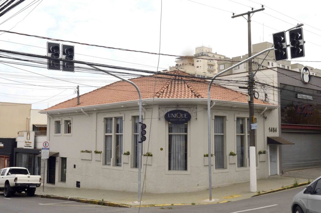 Novos semáforos instalados num cruzamento urbano em frente a um imóvel de esquina com fachada clara e telhado de telhas cerâmicas.