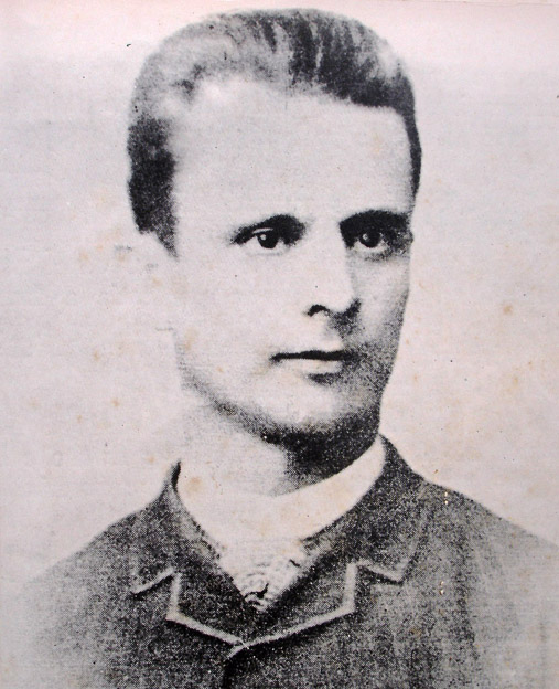 Um retrato monocromático em tom sépia do pintor Almeida Júnior, mostrando o seu rosto de frente com traje formal.
