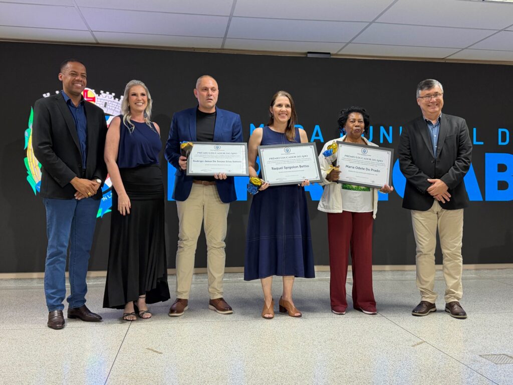 Servidores e profissionais da equipa técnica/administrativa da Educação no palco a receberem os seus diplomas de mérito e flores.