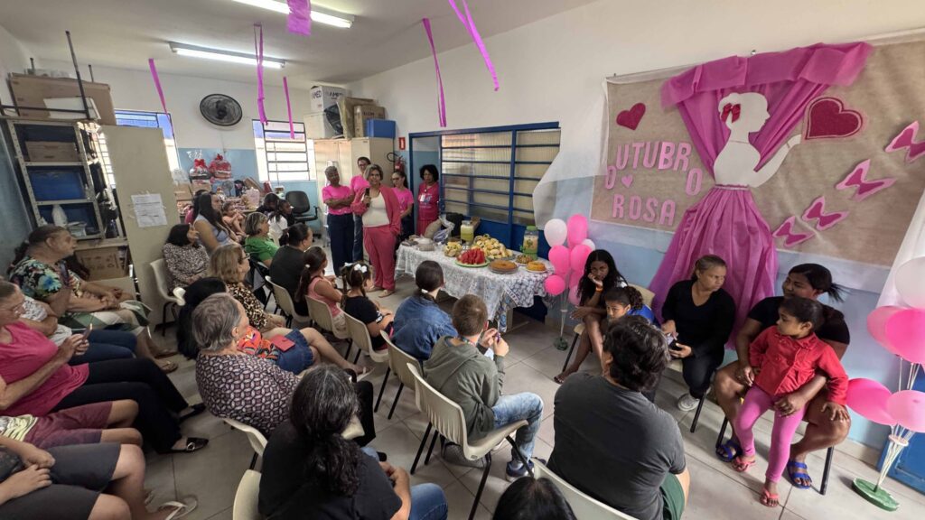 Uma palestra informativa realizada pelo grupo Amigas da Onça na USF Itapuã, com a presença de diversas pessoas num espaço decorado em tons de rosa.