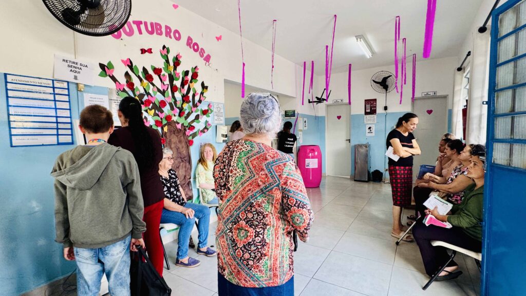 Sala de espera decorada da USF Itapuã com pacientes a aguardar atendimento do Outubro Rosa.